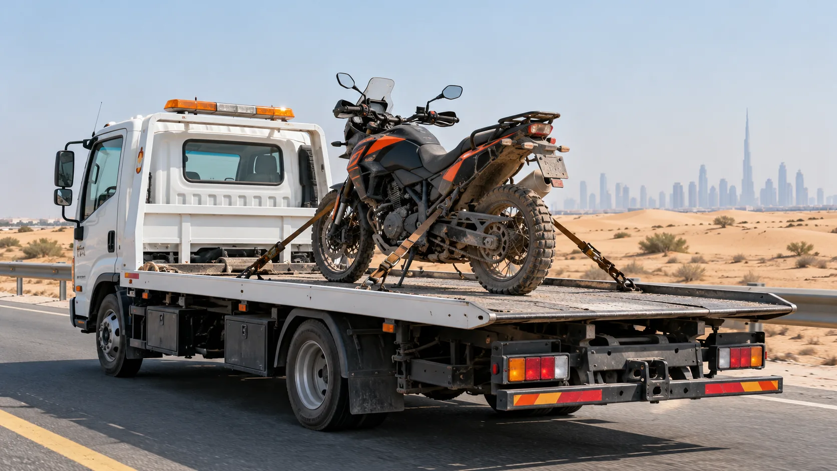 Orange adventure motorcycle secured on a white flatbed near the Dubai desert.